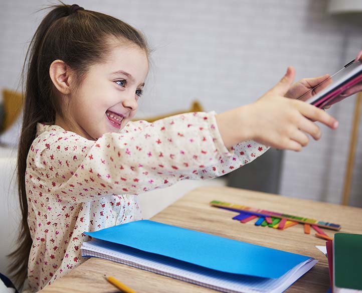 Young girl reaching for a tablet, excited to learn.