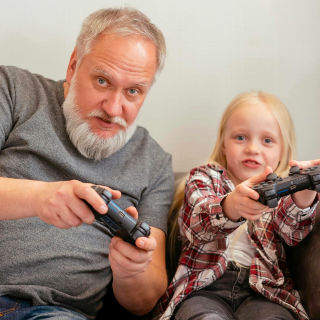 Games Based Learning - Man and Little Girl Sitting on Couch Playing Video Game