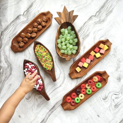 Bowls of different types of candy sitting to table top. Hand of child reaching for candy