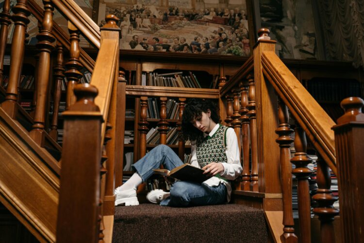 Homeschool History: Historical Reading, Writing, and Thinking - Person Sits on Landing of Beautiful Wooden Staircase Reading Books