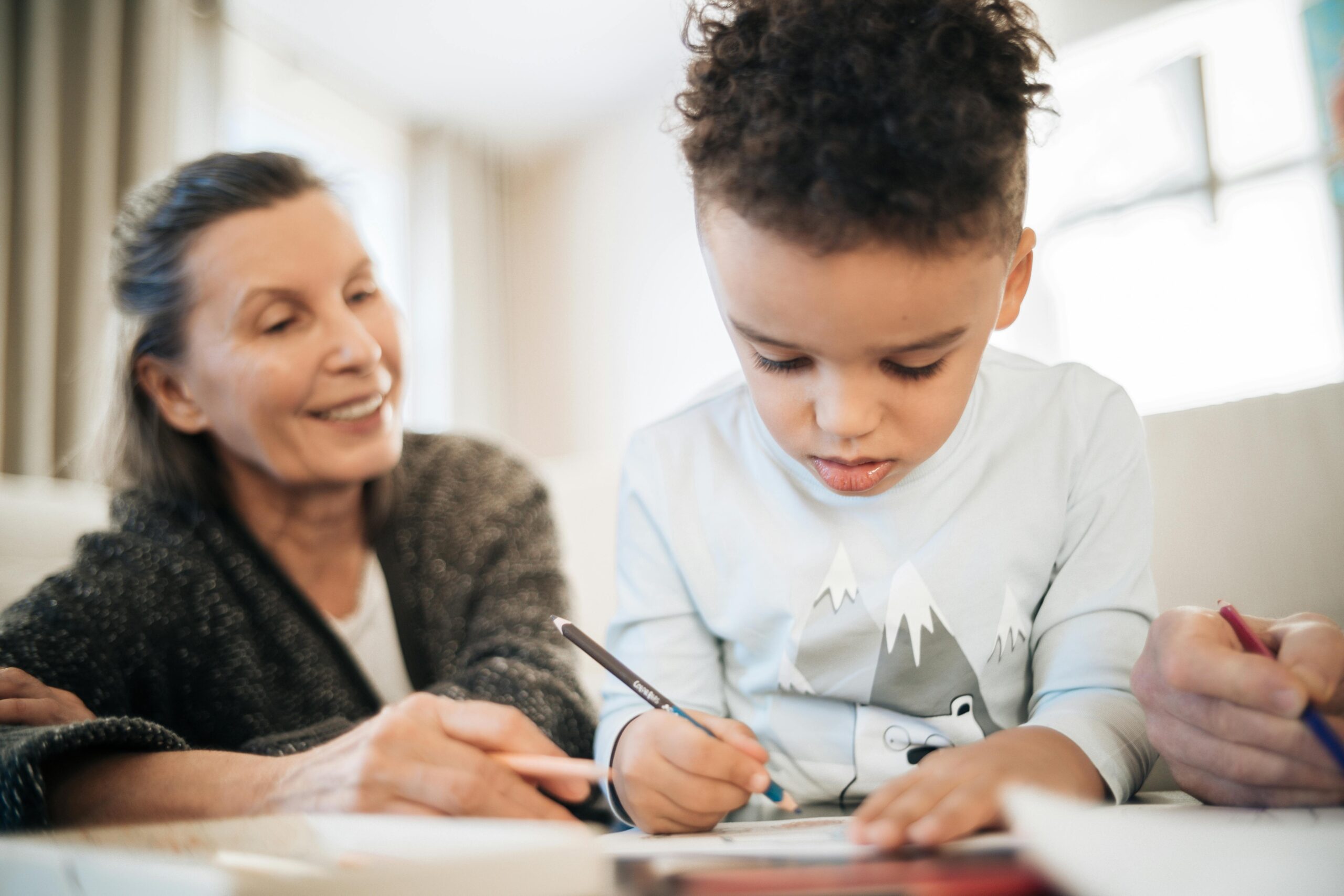 Homeschool History: Historical Thinking, Researching, and Writing - Child writing at table with adult looking over shoulder encouragingly