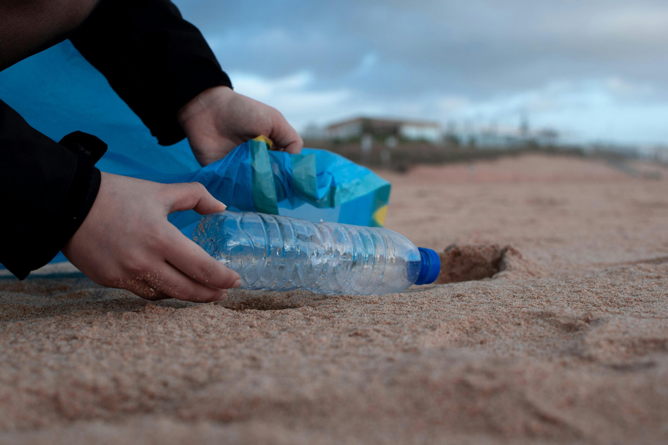 How to Talk to Kids About Scary Science: Person Picking Up Plastic Water Bottle and Putting It into Garbage Bag