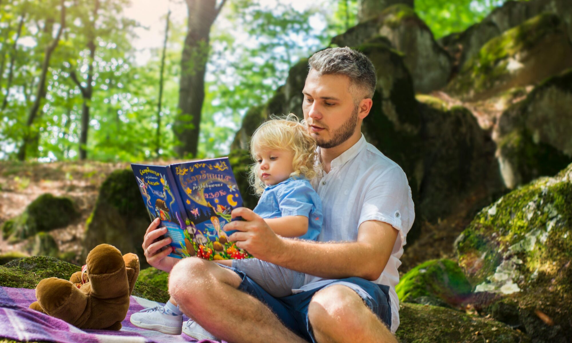 Diverse Books for Children: LGBTQ+ Booklist - Man and Child Sitting in the Forest Reading a Book.